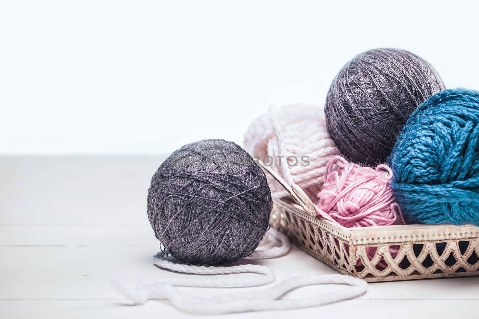 The balls of wool on blue studio background on wooden table