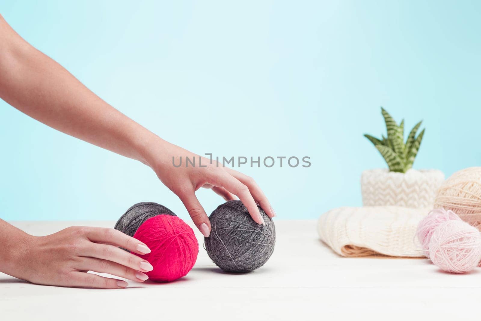 The balls of wool and female hands on blue studio background