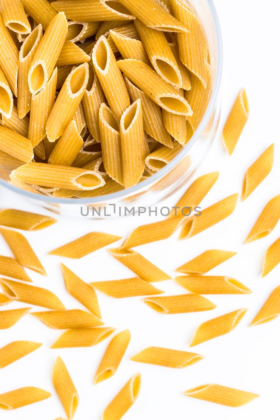 Italian dry pasta in the shape of pens in a glass bowl.