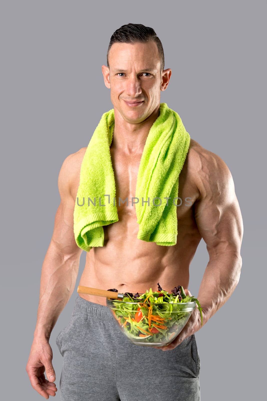 Powerful athletic man with great physique eating a healthy salad.