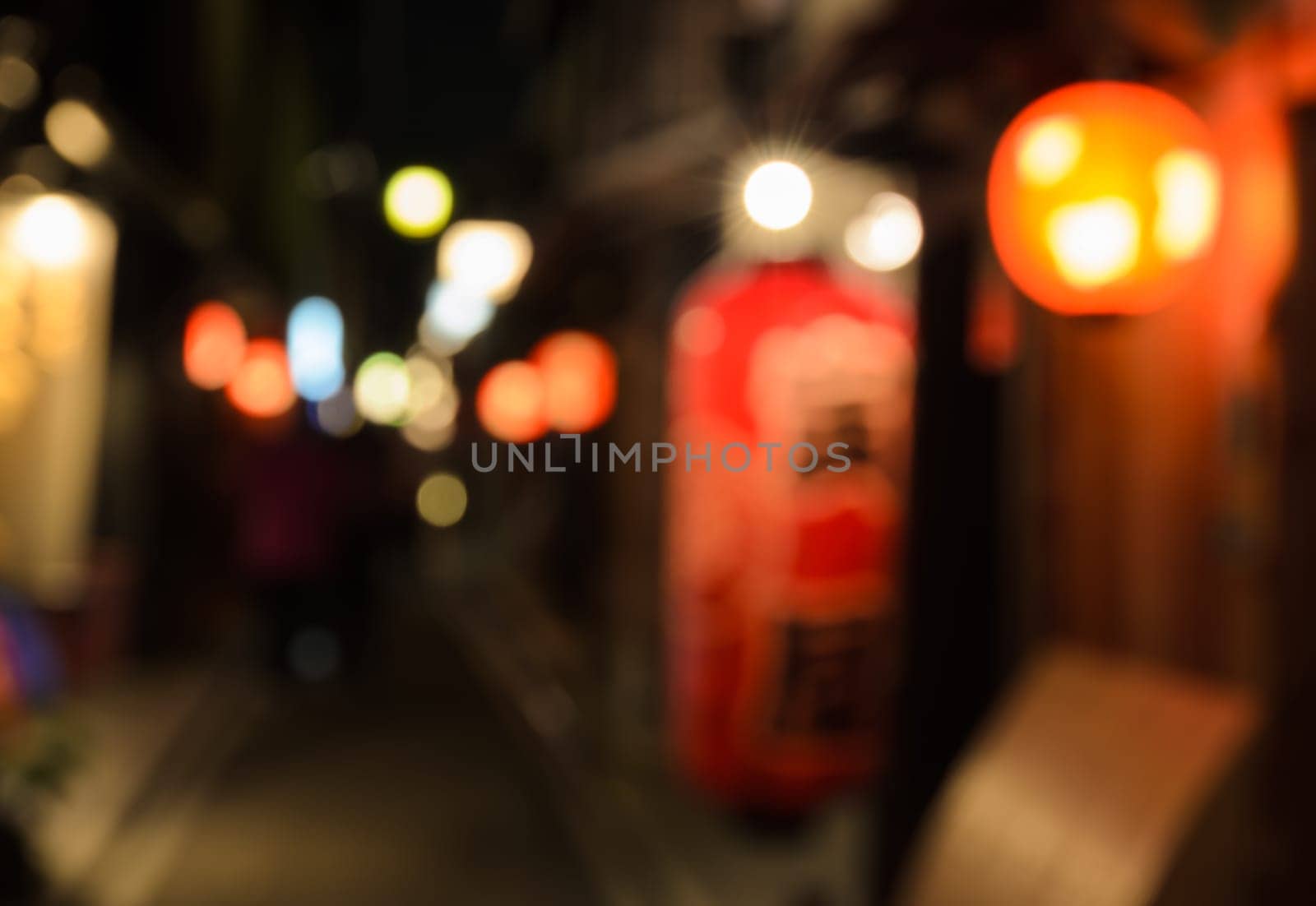 Abstract blur people walking on narrow street of wooden store and restaurant with lighted lantern at night in Kyoto, Japan