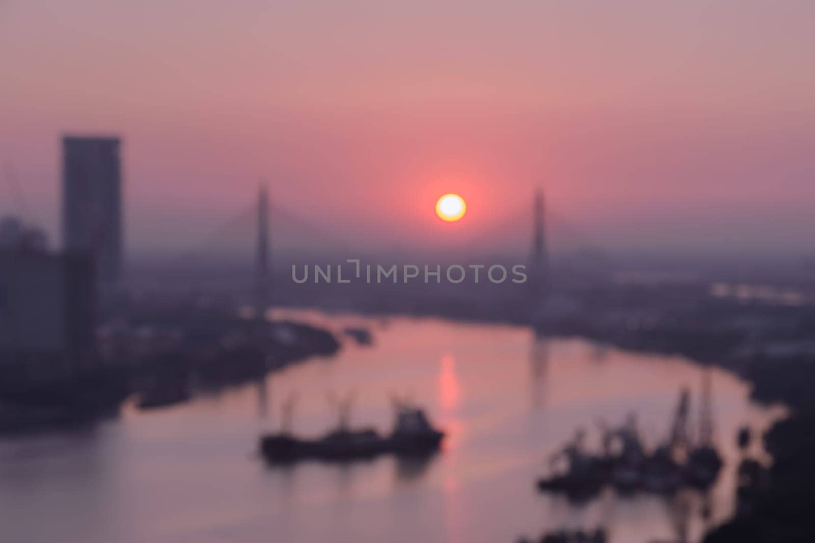 Blurred aerial view of riverside city skyline on golden warm sunrise over the cable bridge in Bangkok, Thailand