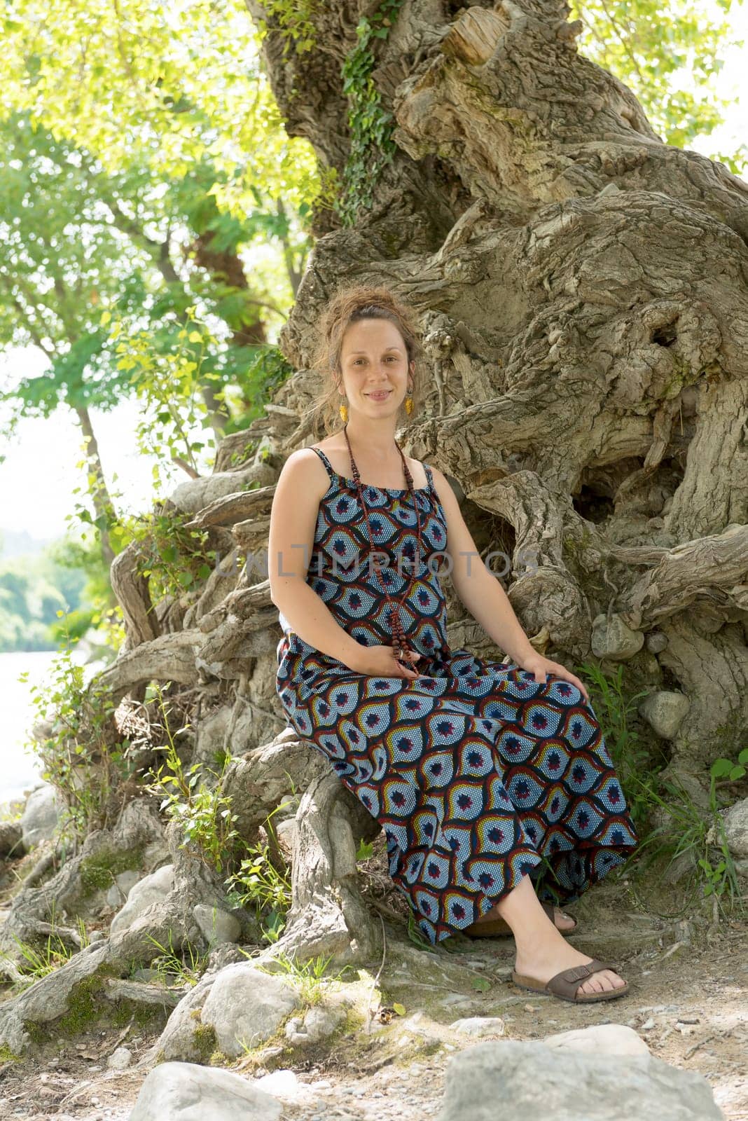 a beautiful pregnant woman sitting under a tree
