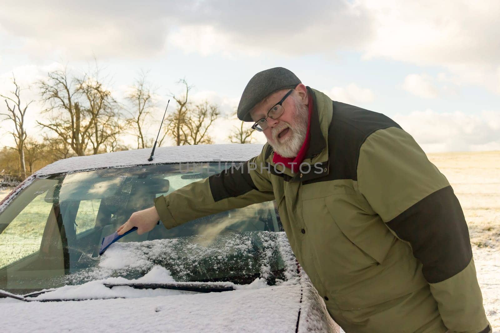 Senior frees car window from frost and snow