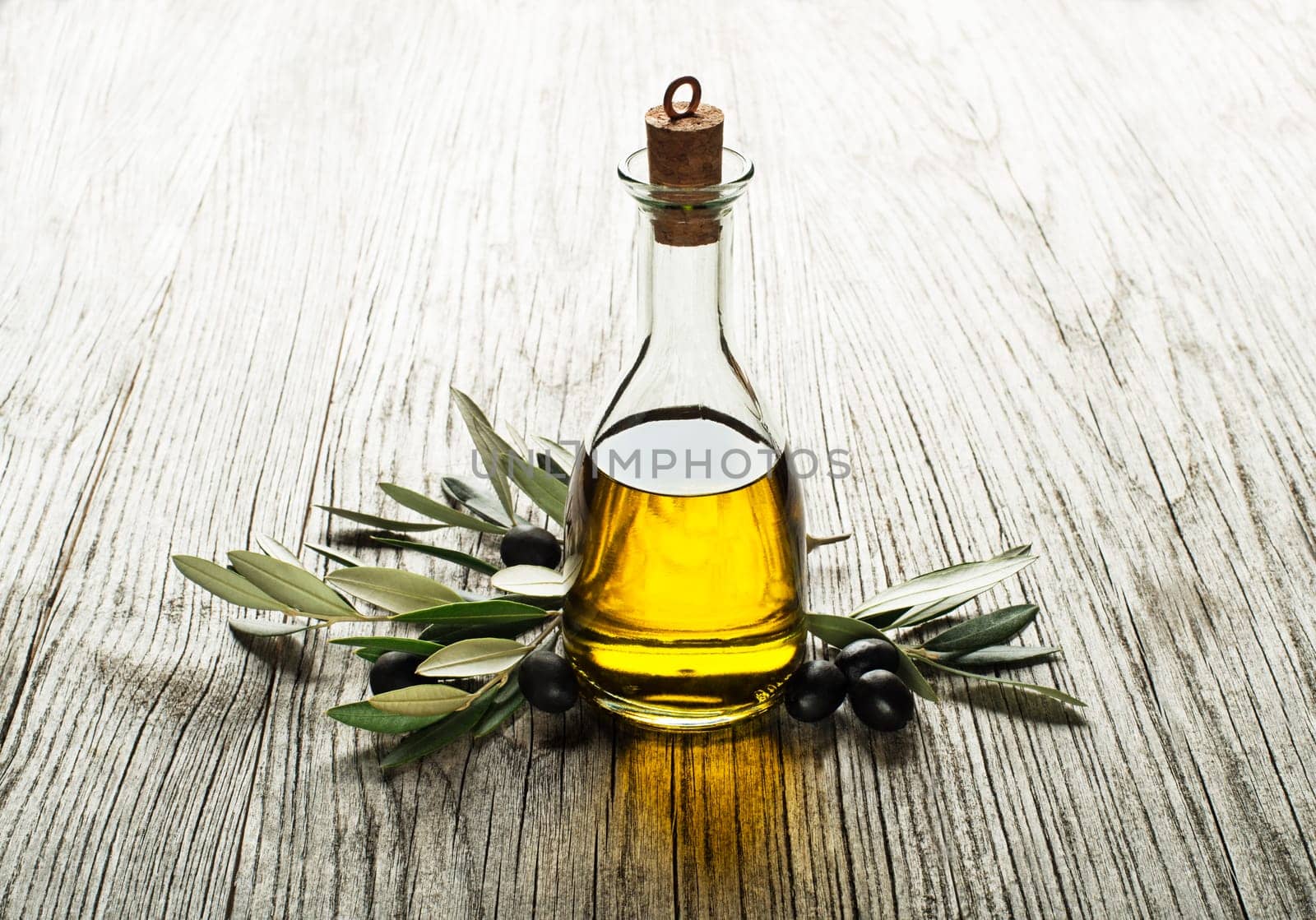 Olive oil and olive branch on a wooden background