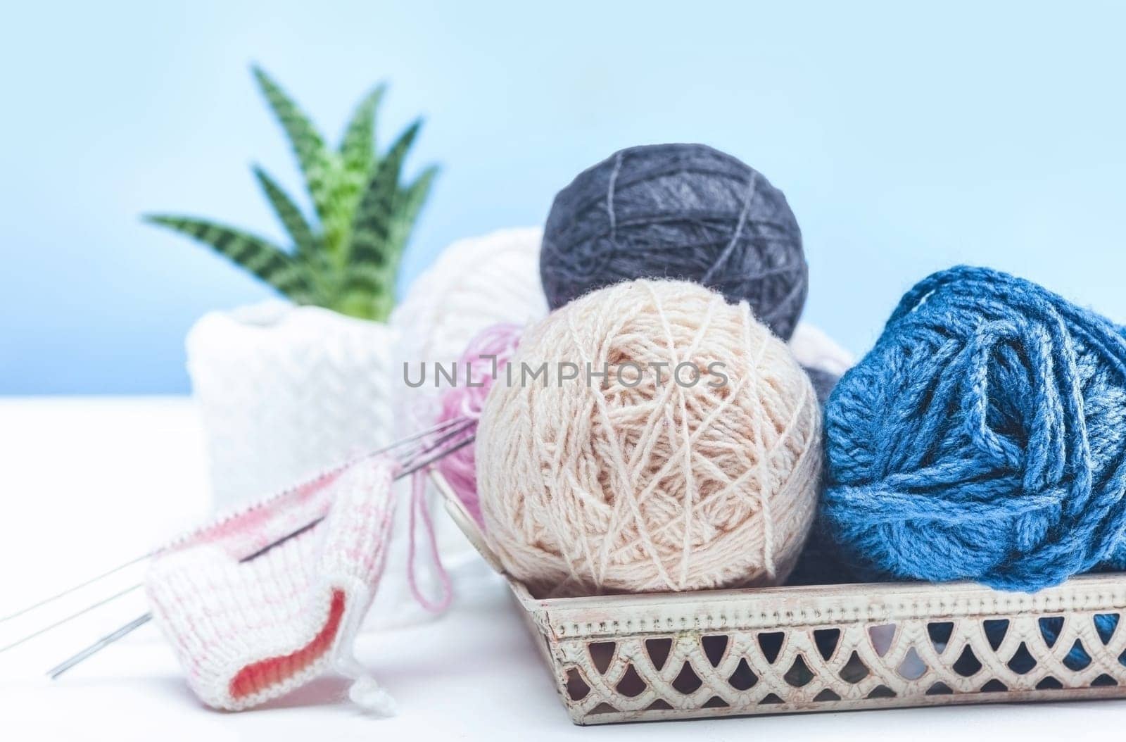 The balls of wool and needles on blue studio background