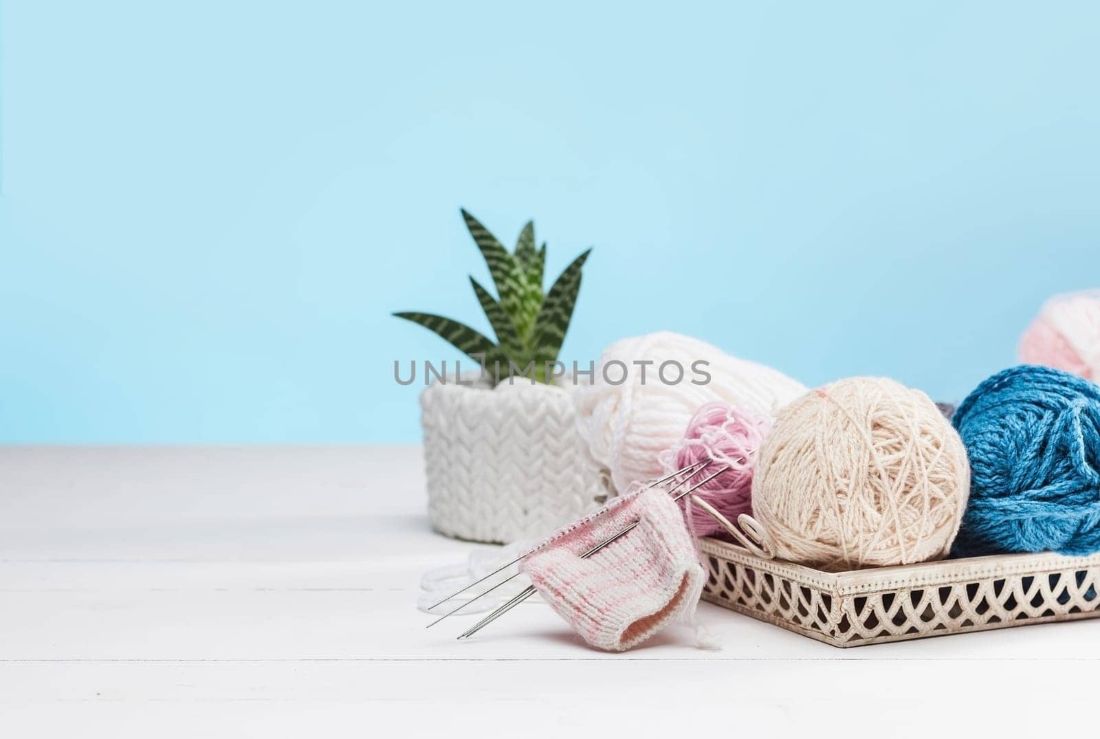 The balls of wool and needles on blue studio background