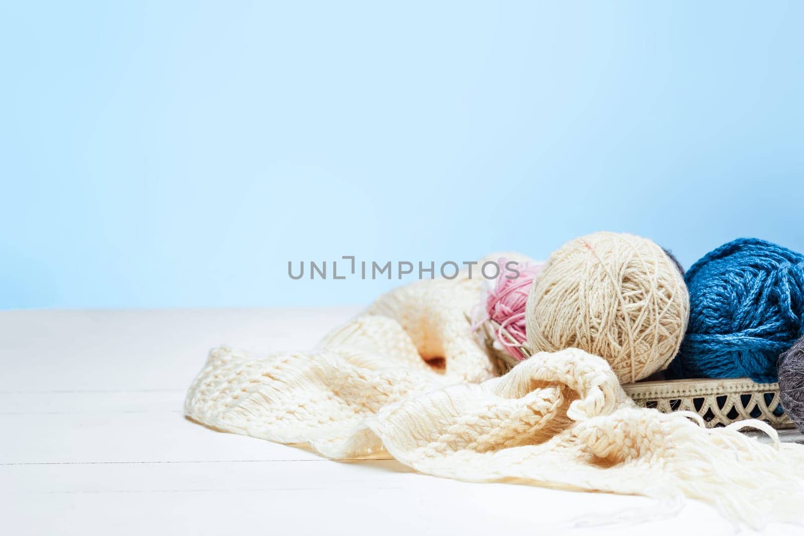 The balls of wool and needles on blue studio background