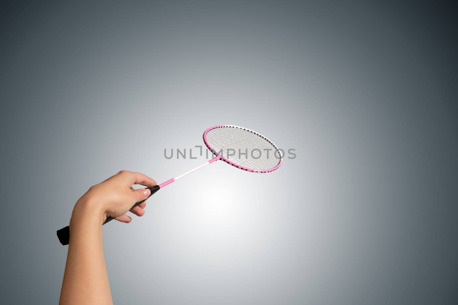 Color photo of one racket for badminton and female hand isolated on gray