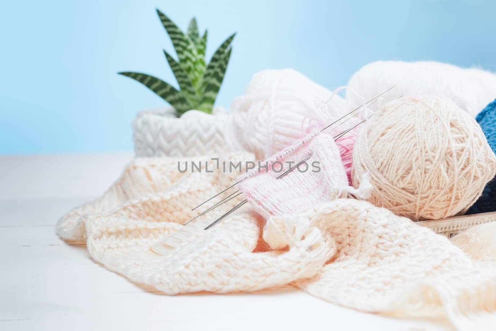 The balls of wool and needles on blue studio background