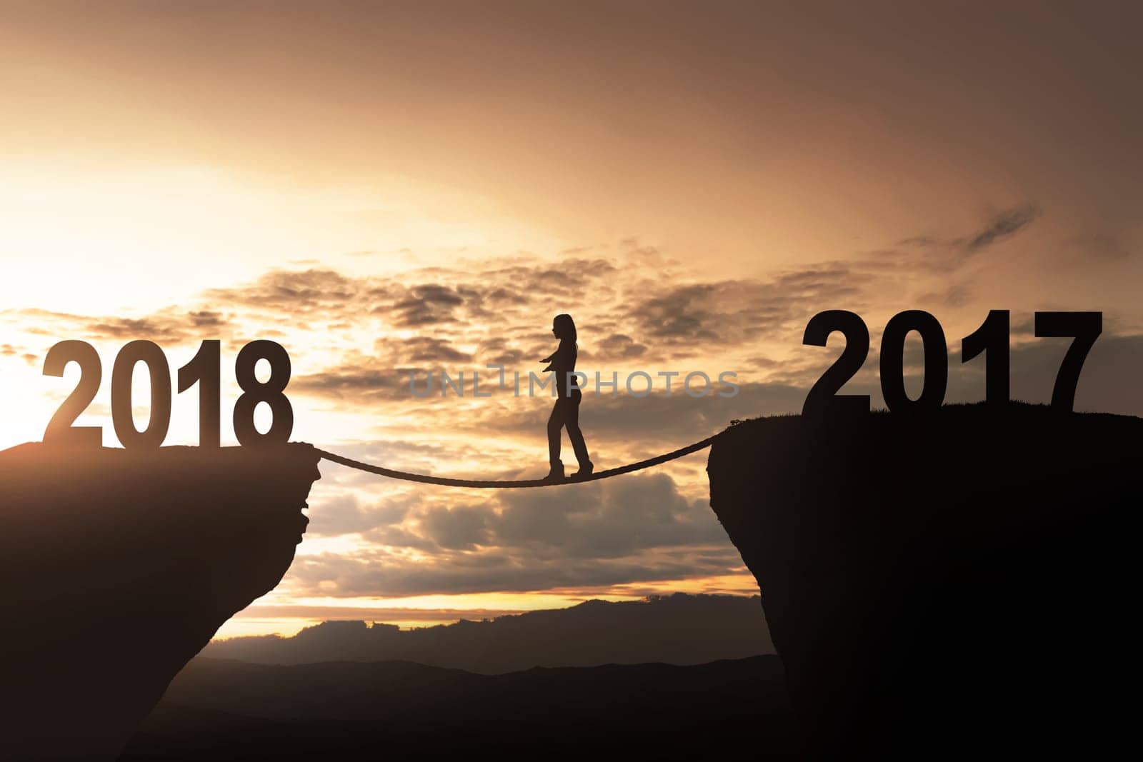 Silhouette of woman crosses the rope towards 2018 with sunset background