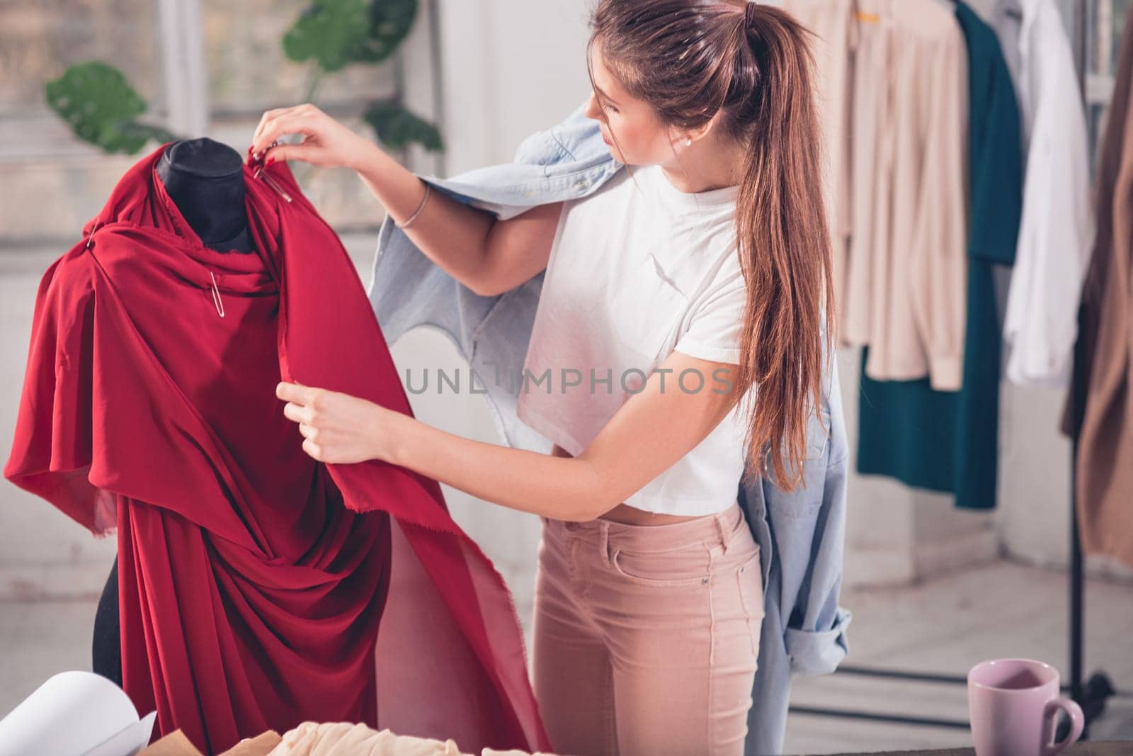 The female fashion designer working in studio sitting on the desk