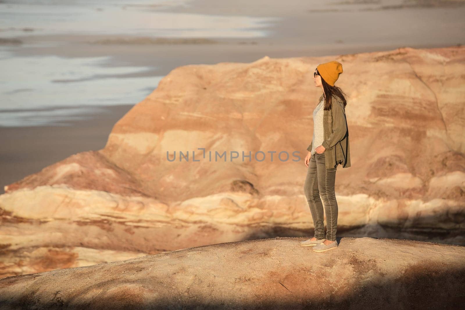 Beautiful woman with yellow cap over the cliff seeing the beach