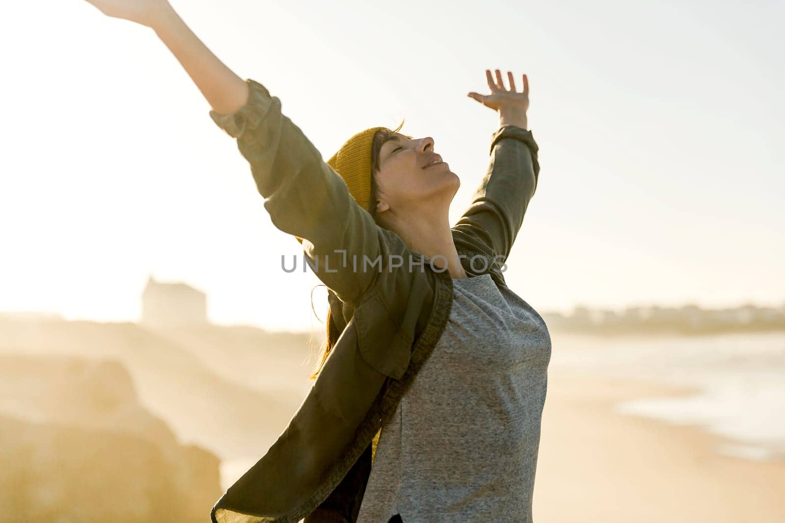 Beautiful woman with yellow cap over the cliff seeing the beach
