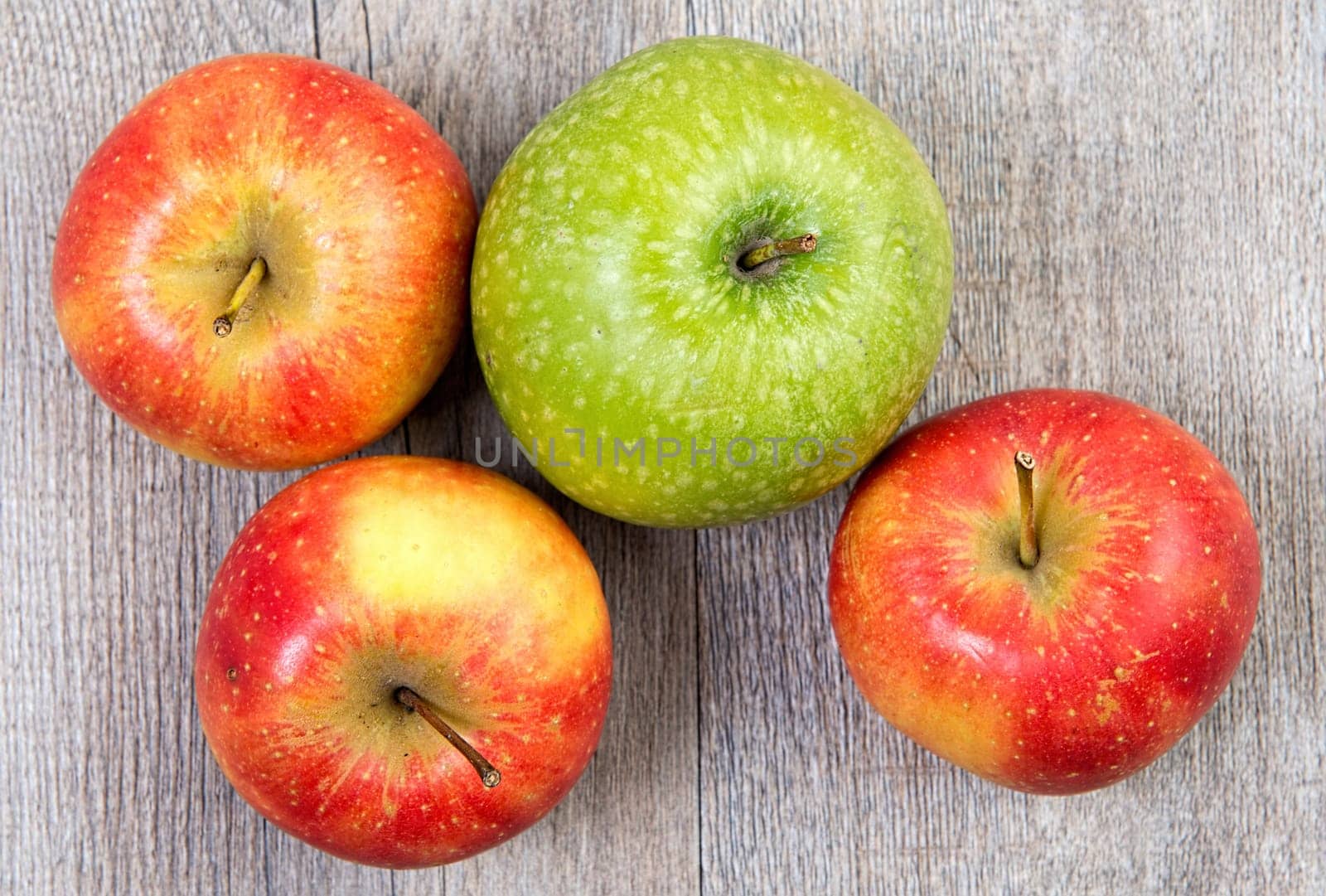 green and red apples placed on a wooden table
