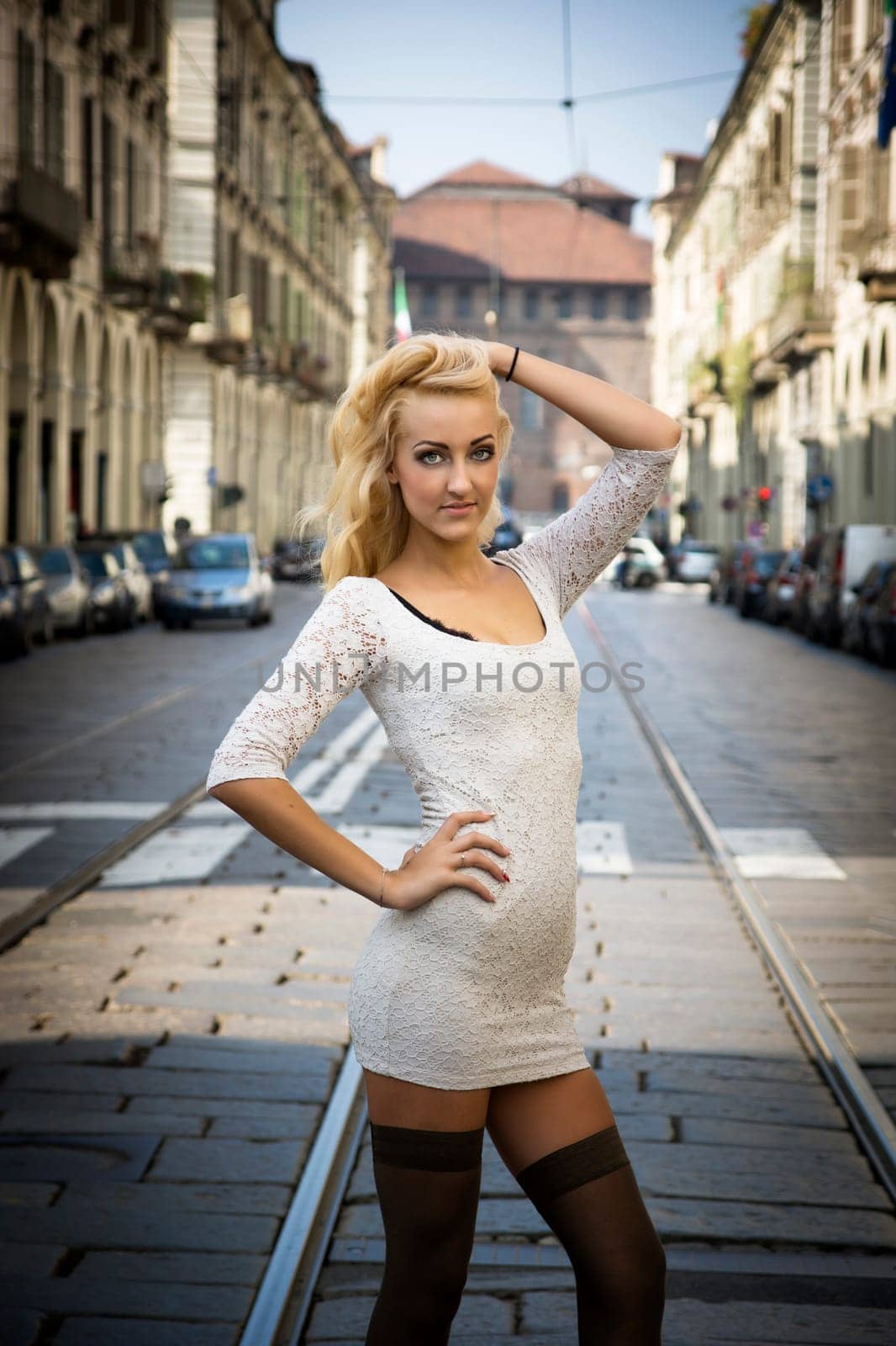 Pretty Young Blonde Woman in Sexy White Dress in Turin City Center, Italy. Captured with Street and Architectural Buildings at the Back.