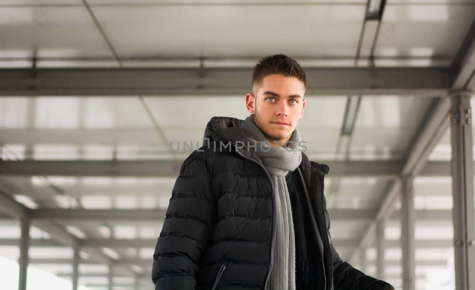 Attractive young man under tunnel in urban environment, looking at camera, wearing winter clothing