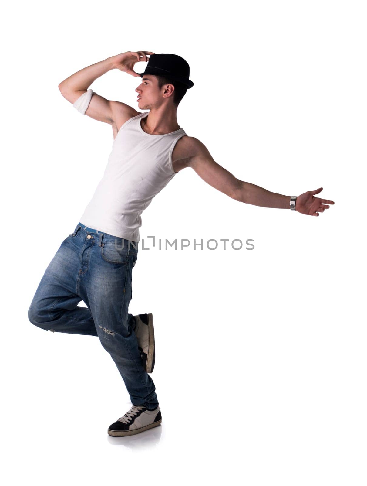 Hip young man in a tank top and hat doing a dance routine posing on one leg, isolated on white background