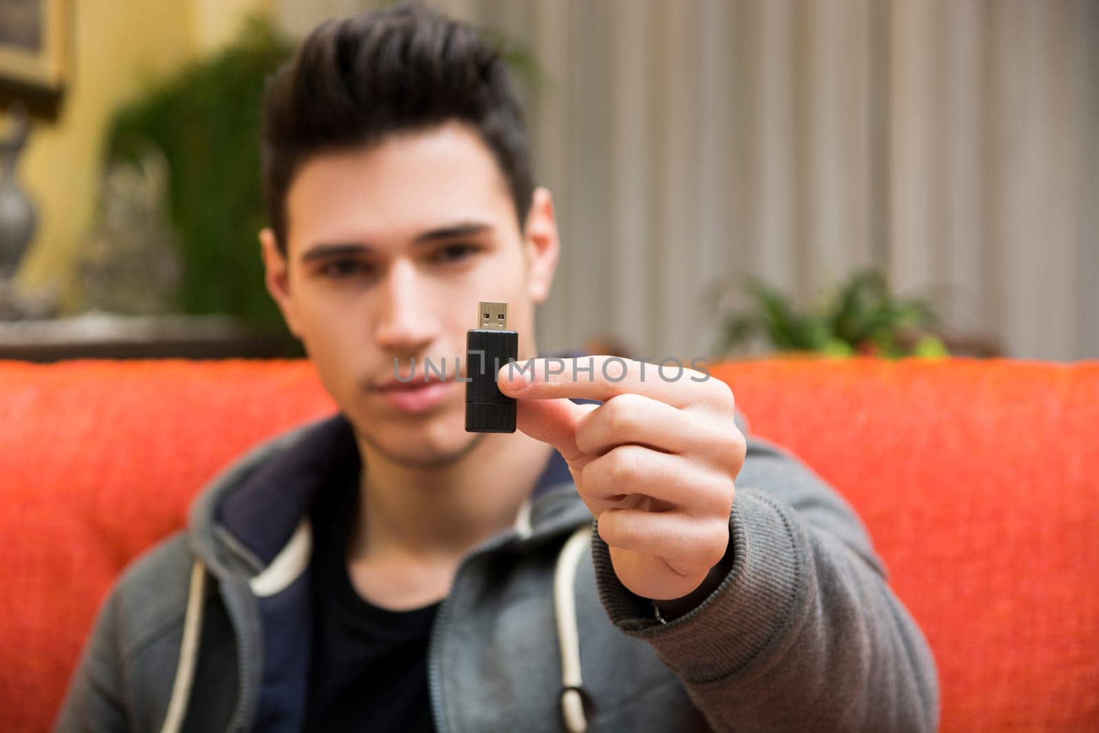 Handsome young man showing USB key in his hand, focus on the electronic drive