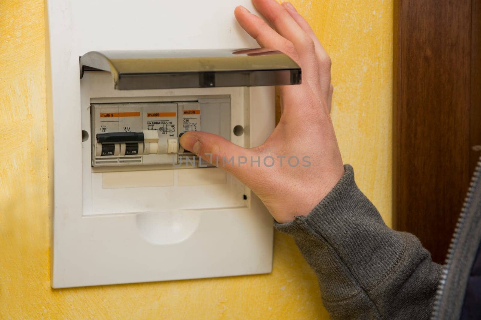Close up of male hand using an electronic control panel, to switch on electricity at home