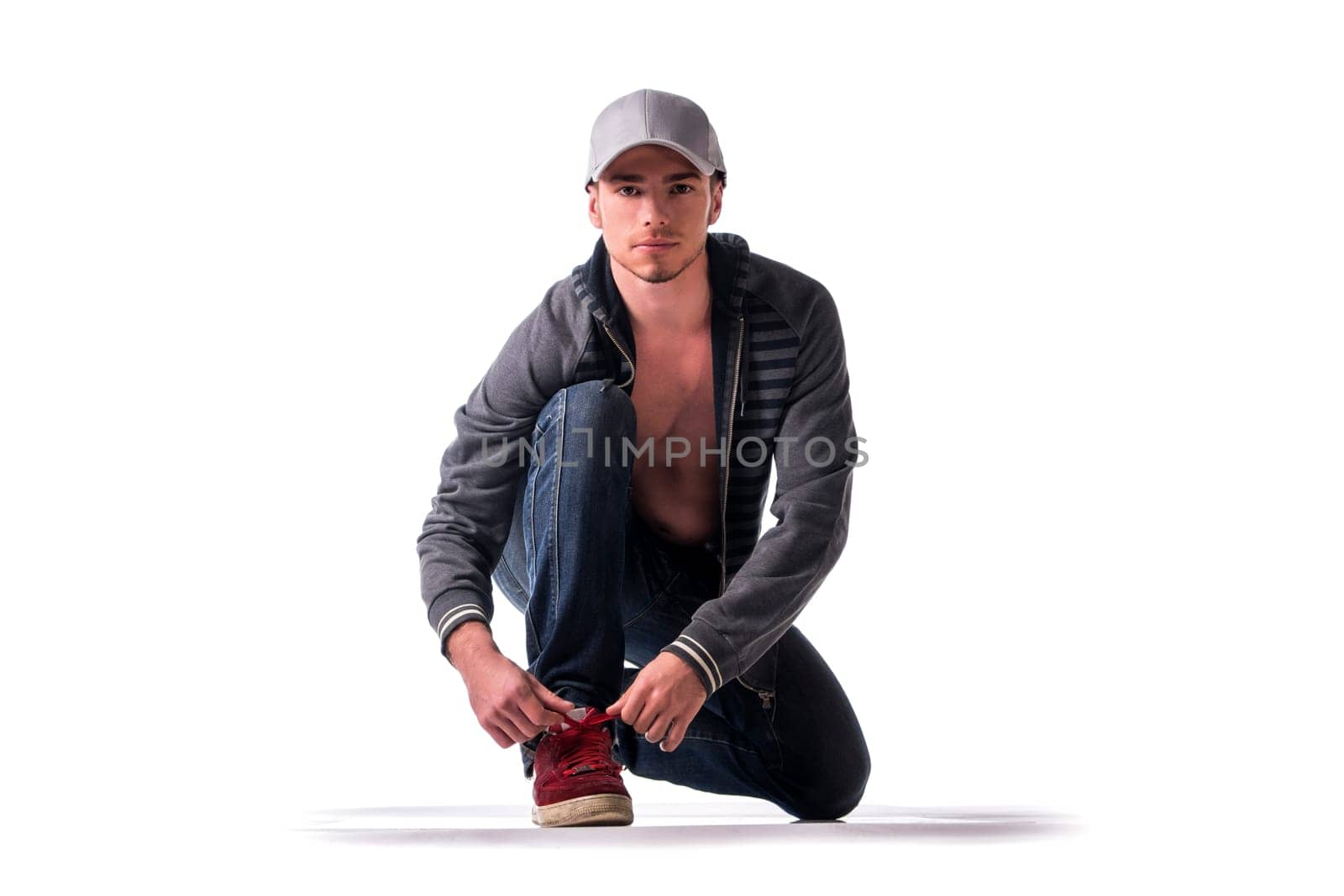 Handsome young man kneeling and tying sneaker show, ready to run. Isolated on white