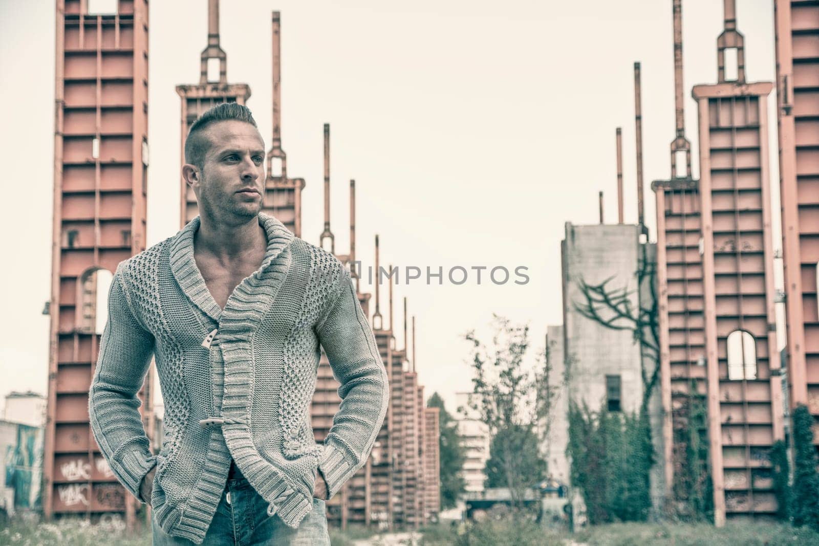 Handsome muscular blond man standing in city setting or former industrial environment