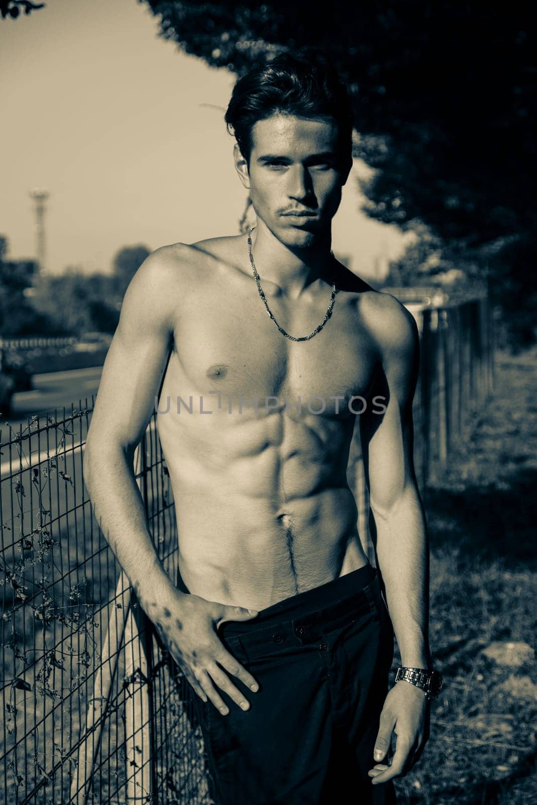 Handsome shirtless young man and road busy with cars and traffic in background