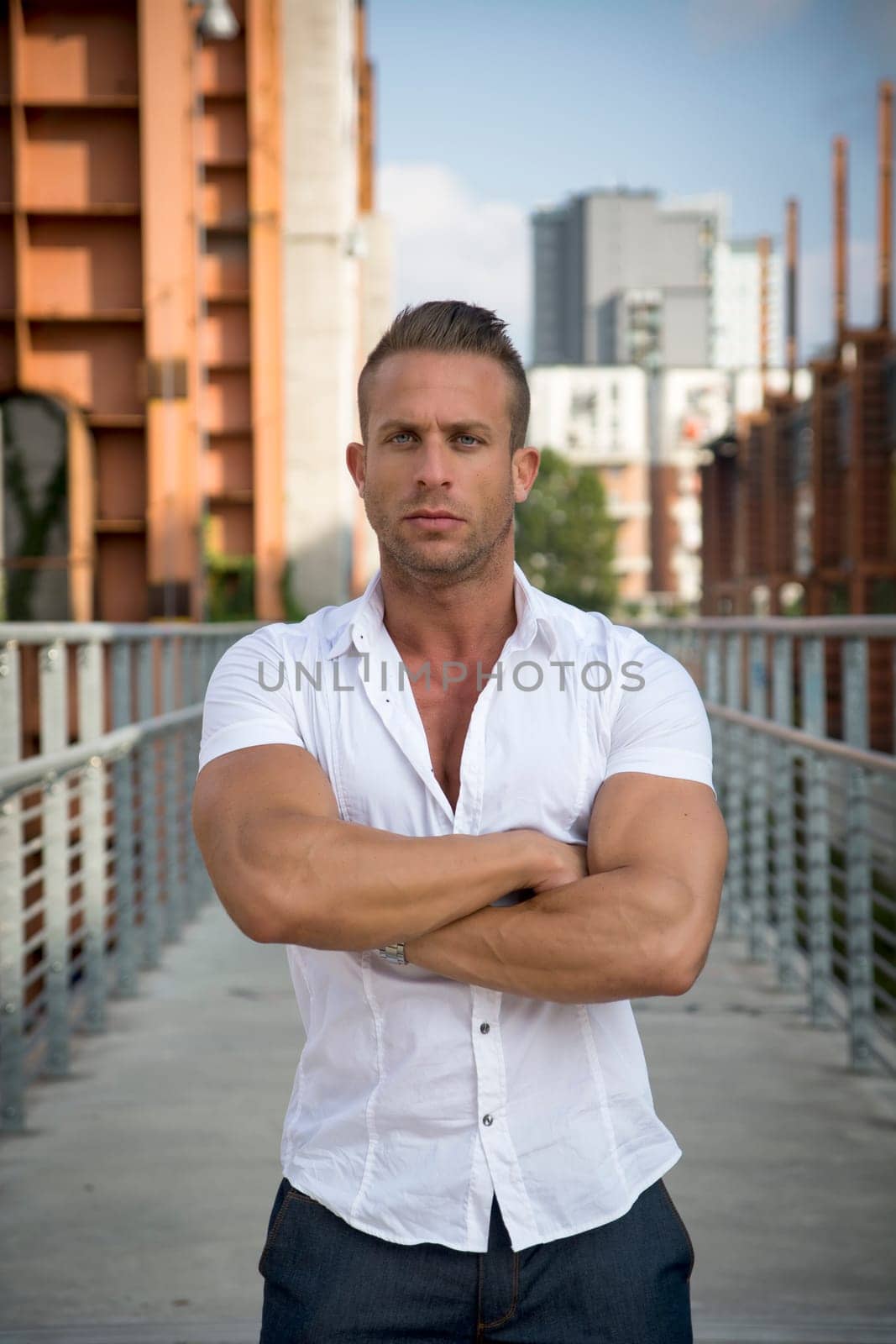 Handsome muscular blond man standing in city setting or former industrial environment