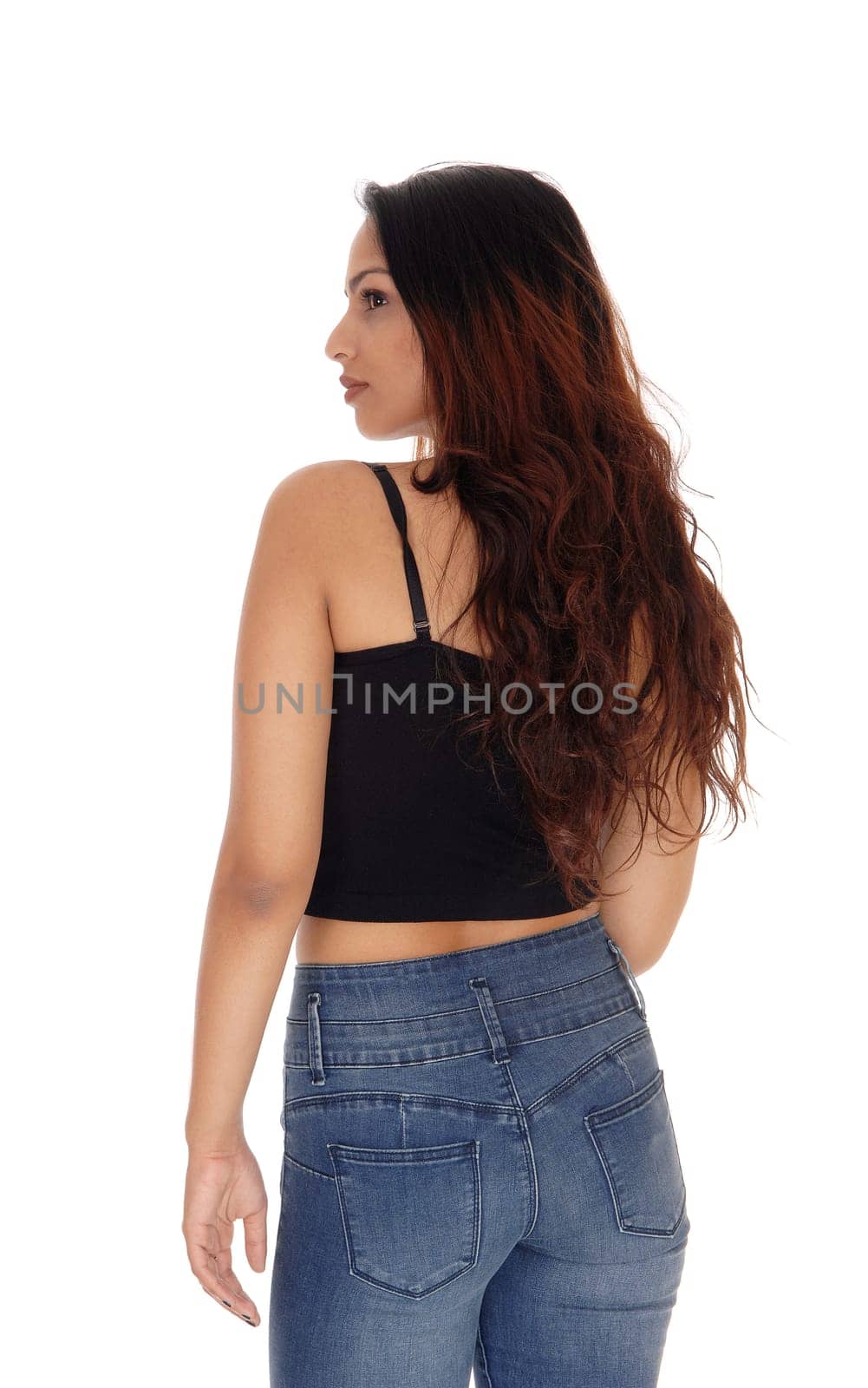 A beautiful young woman standing in jeans and a black corset with.brunette hair, isolated for white background.
