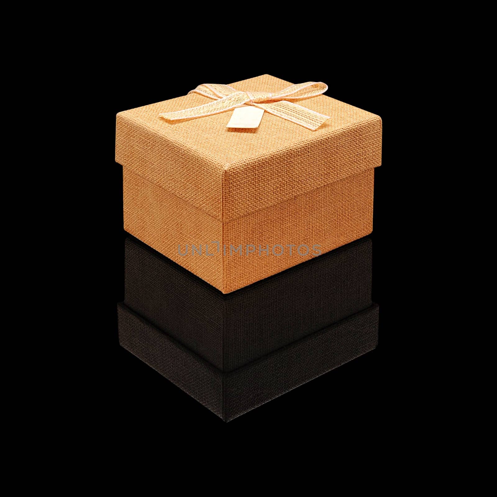 Gift box close fabric texture beige with a bow on a black glossy background with real reflection. Isolated.