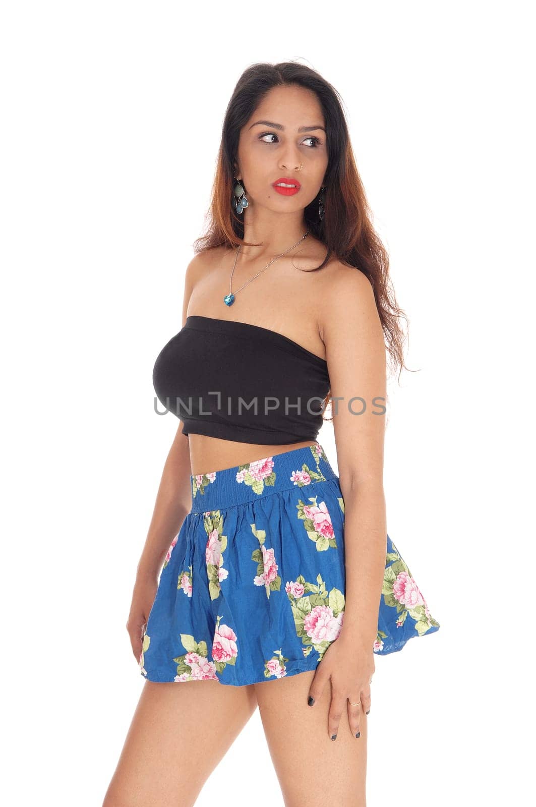 A gorgeous young woman standing in a blue short skirt and black.top, looking away, isolated for white background.