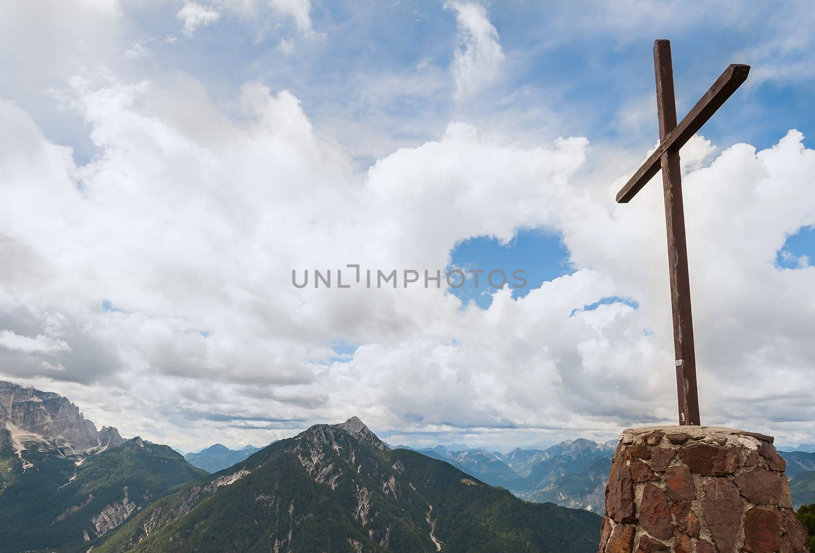 Wooden cross on top of the mountain. Mountain landscape above the clouds. Cross on top of a mountain peak as typical in the Alps.