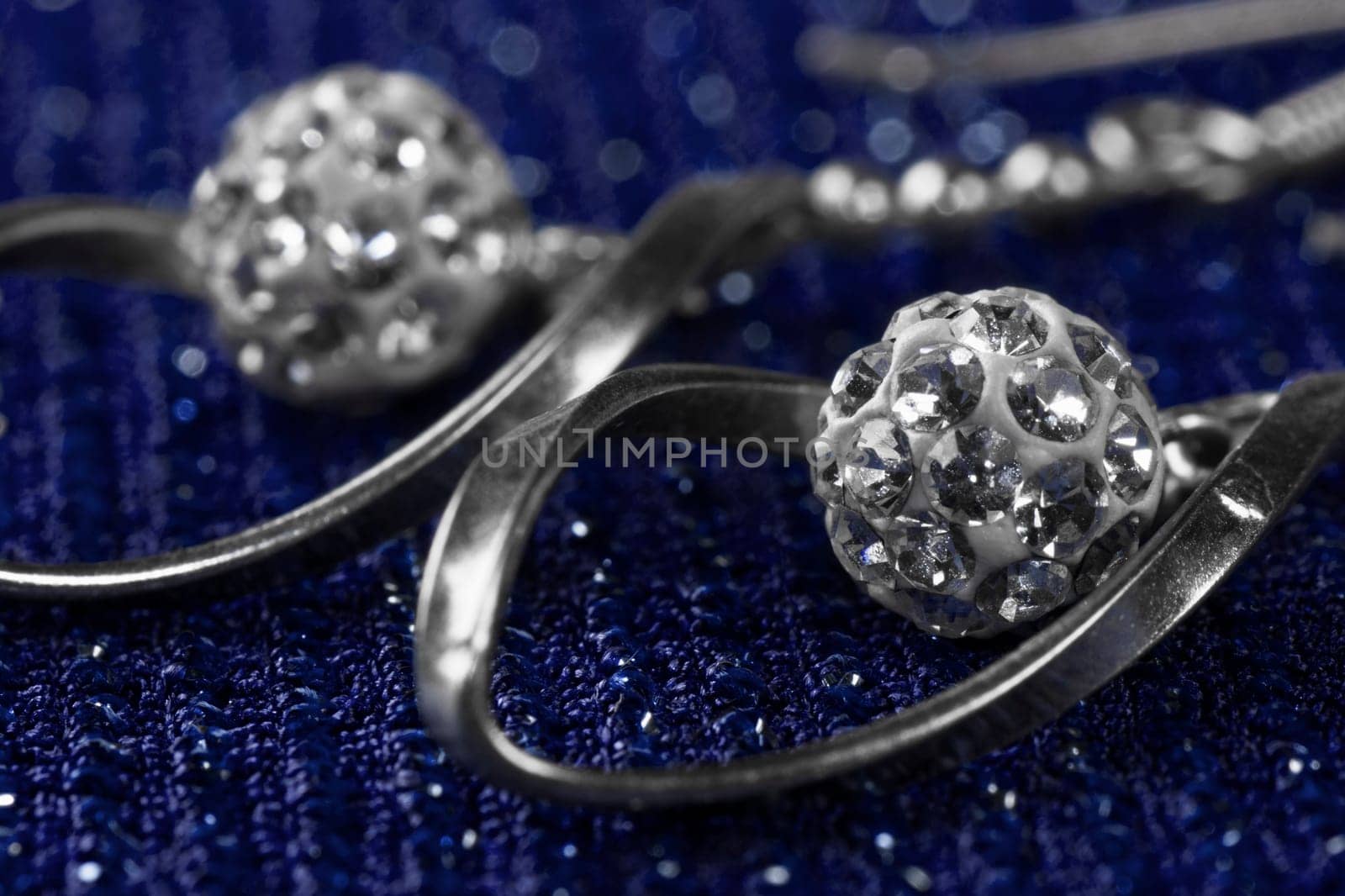Macro photo about luxury silver earrings on dark blue background.