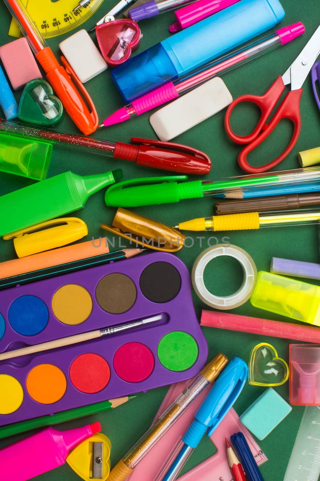 Different school supplies are on green background.