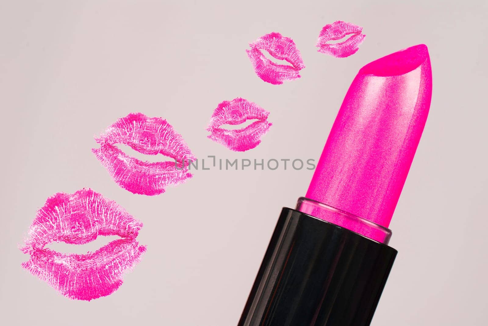 Pink lipstick and pink lipstick kisses are on gray background.