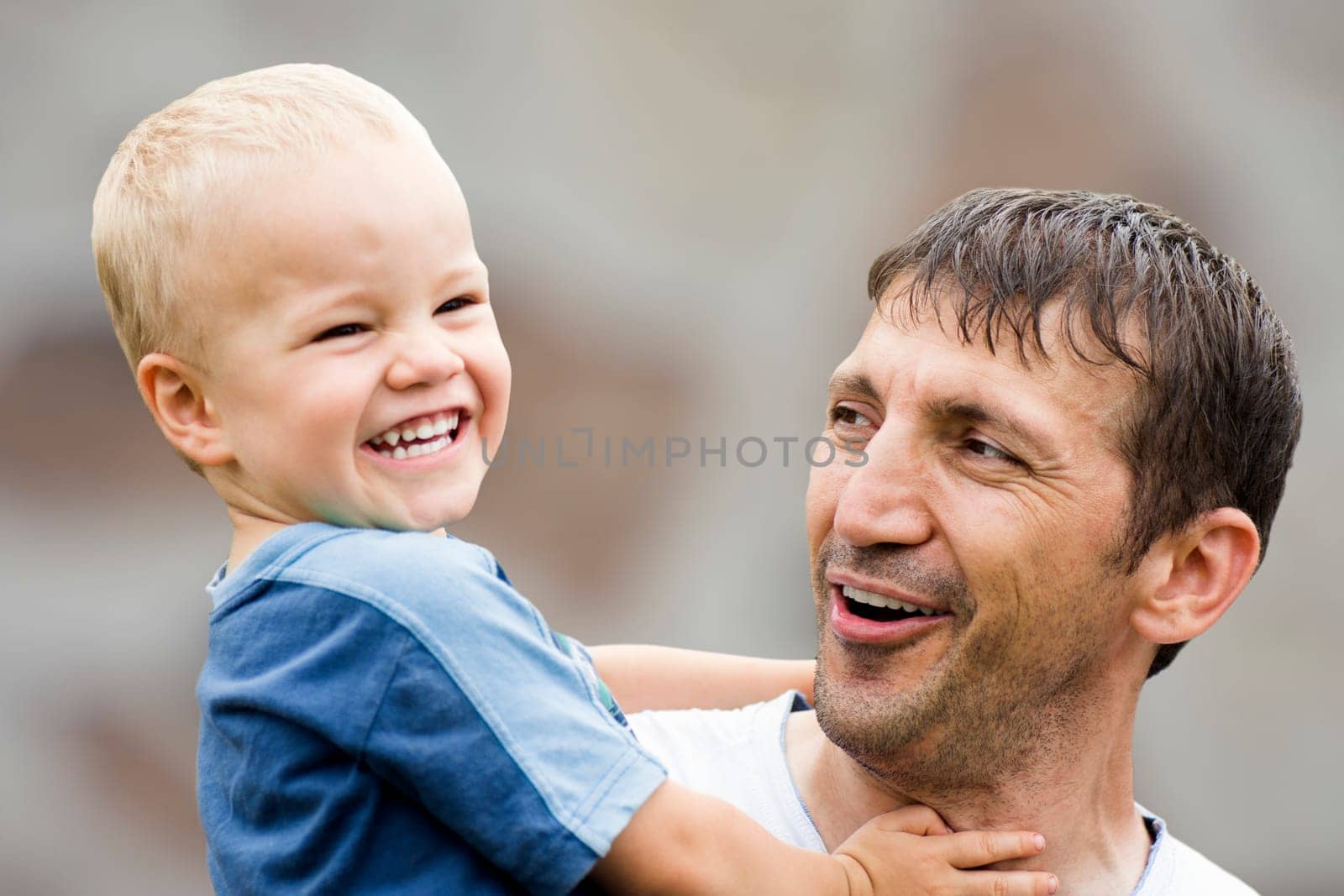 Happy laughing family, uncle and boy on gray background.