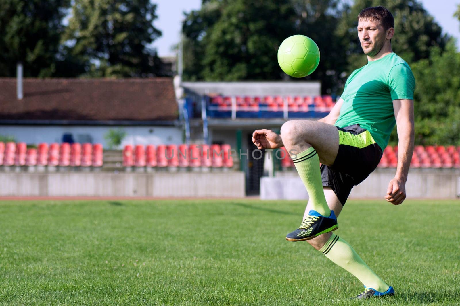 The football player is practicing shoots with the ball on playing field.