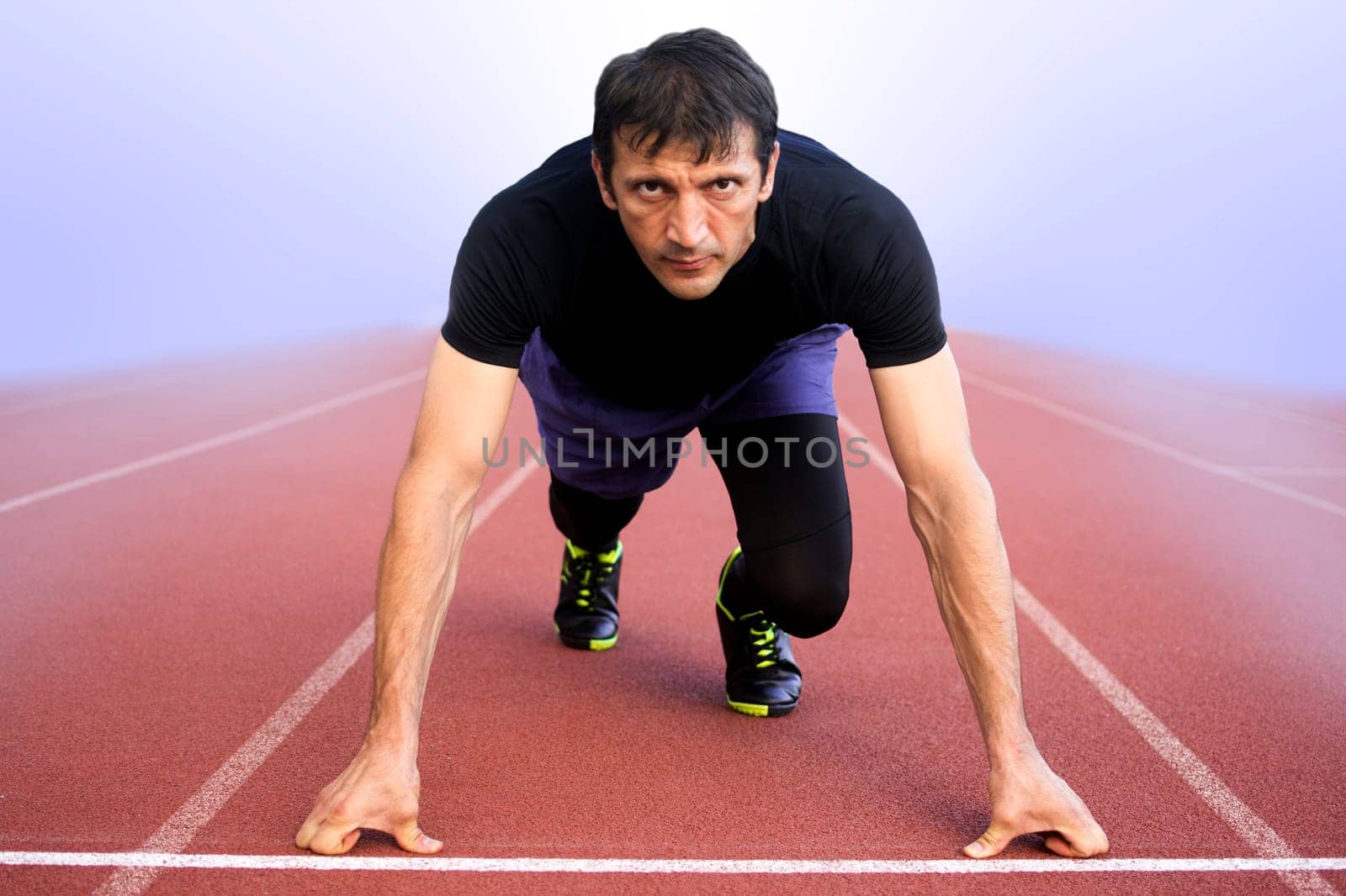 The athlete is ready to run on startline in the fog.