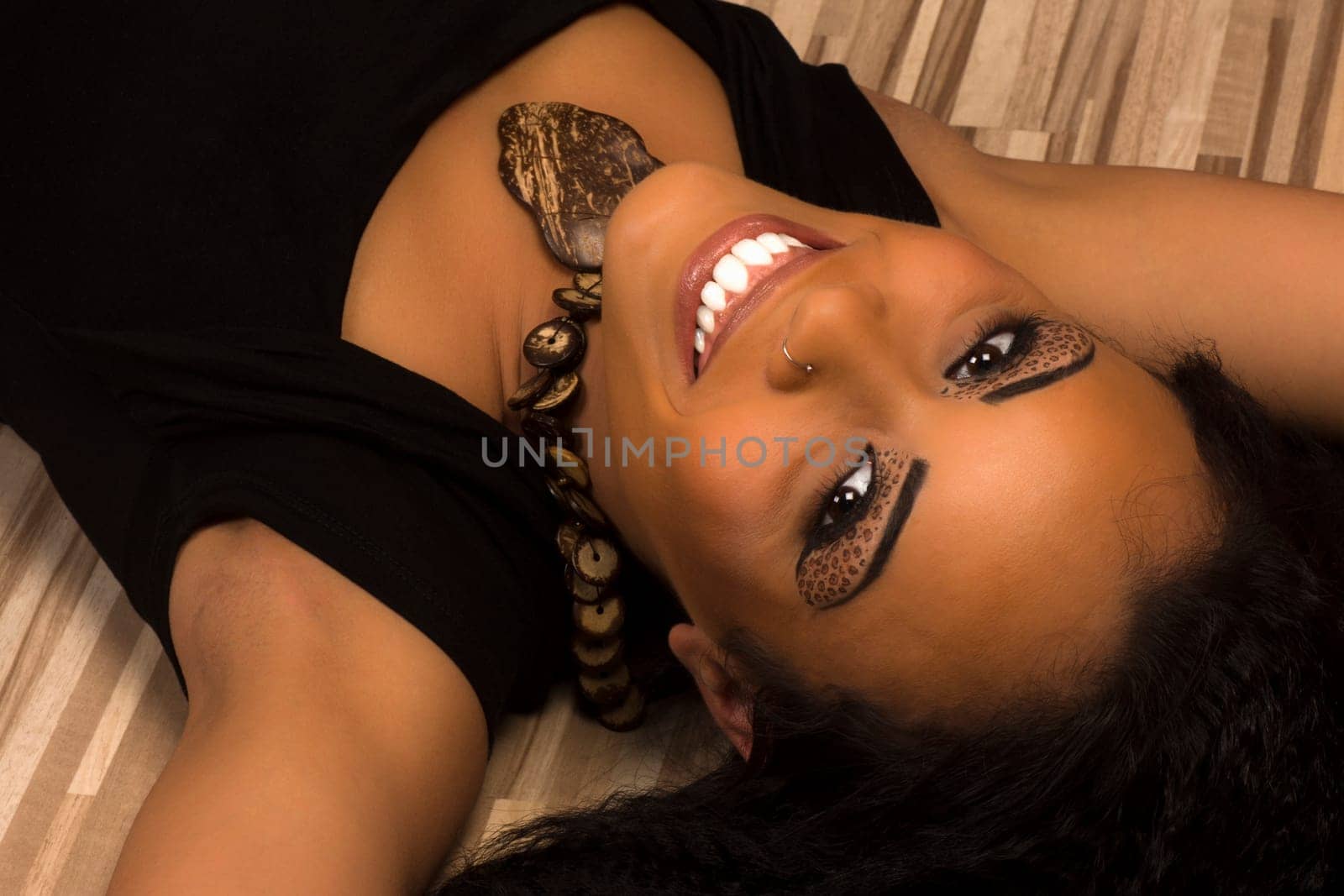 The beautiful smiling woman is lying down.
