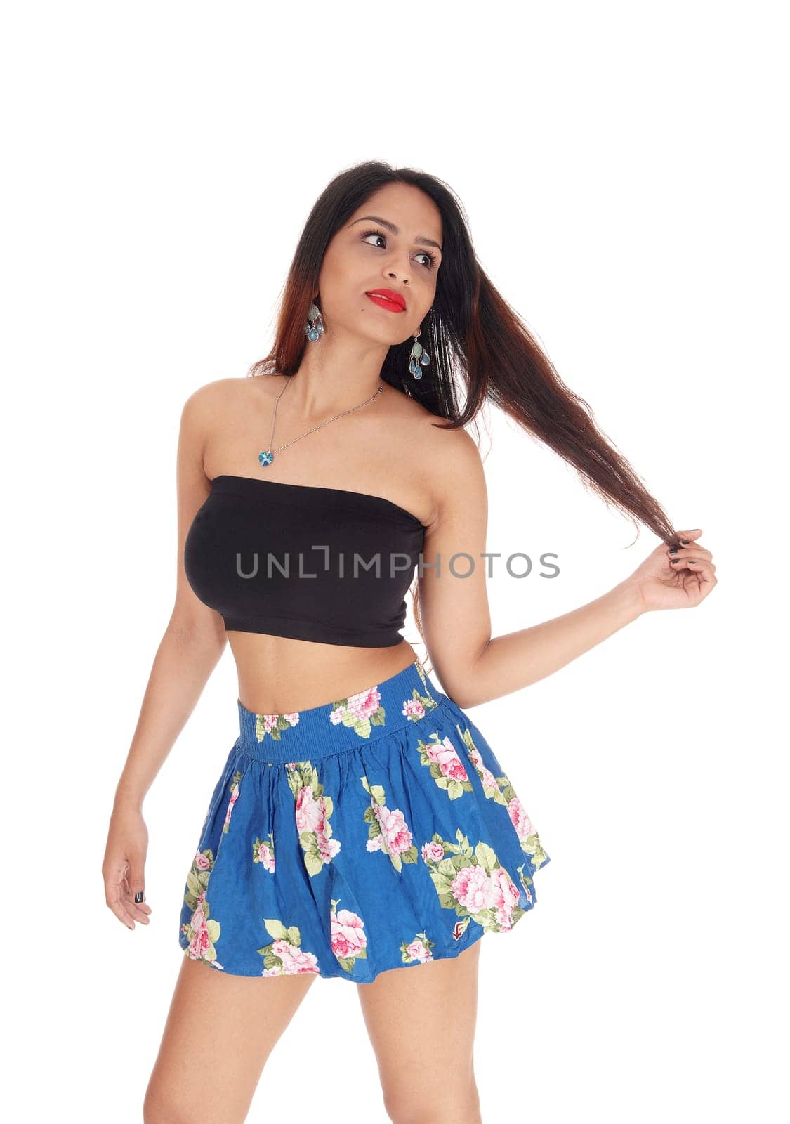A gorgeous young woman standing in a blue short skirt and black.top, looking away, isolated for white background.