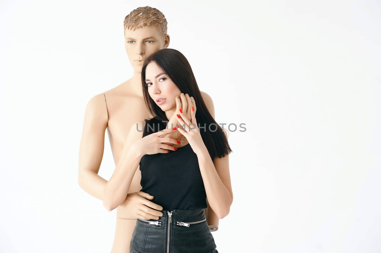 A young woman, dressed in a black leather skirt, and black boots on the tractor sole, the cheeks in the net. Posing with a disassembled male mannequin.