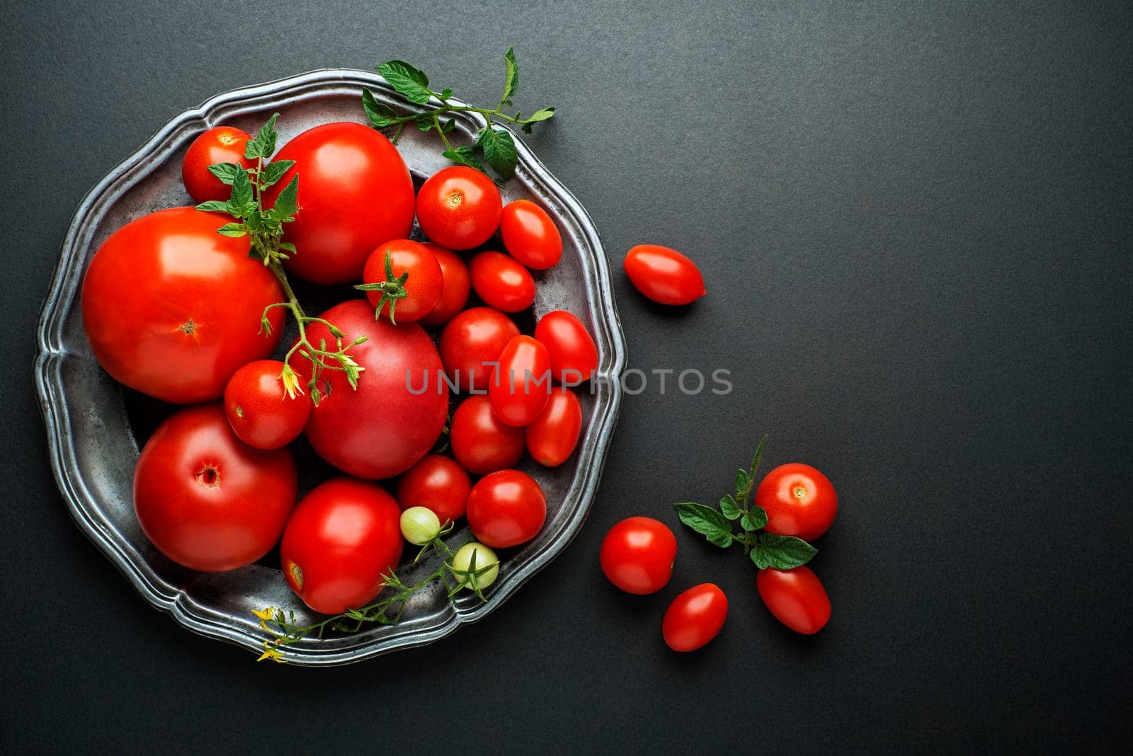 Fresh red tomatoes in a bowl on black background. Top view