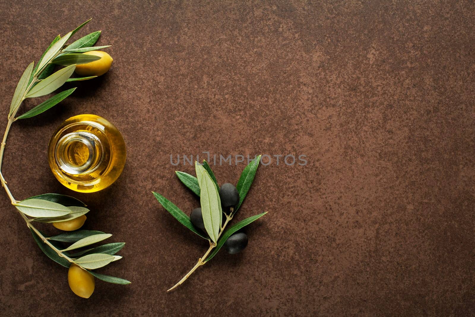 Olive oil and olive branch on brown background