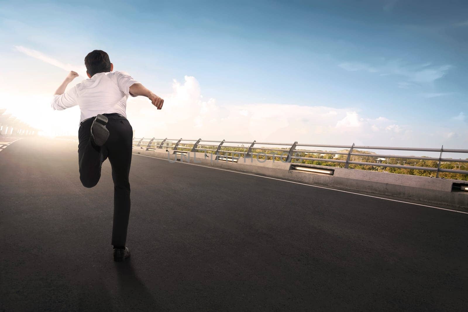 Back view of asian businessman running on the road