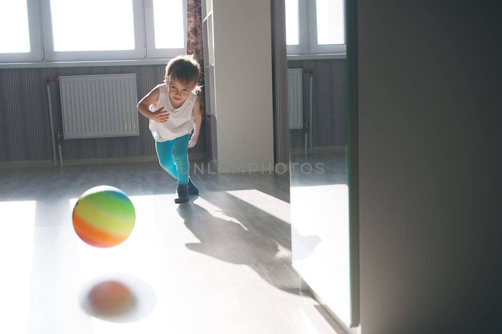 child playing with a multicolored ball in the apartment.