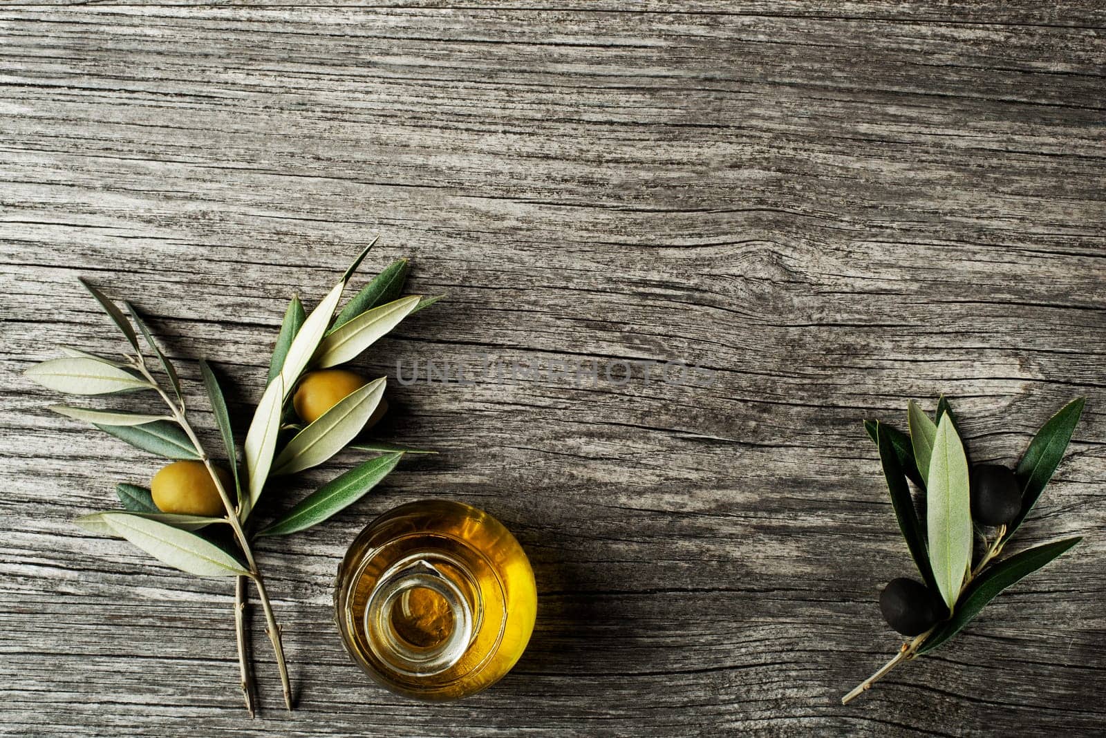 Olive oil and olive branch on a wooden background