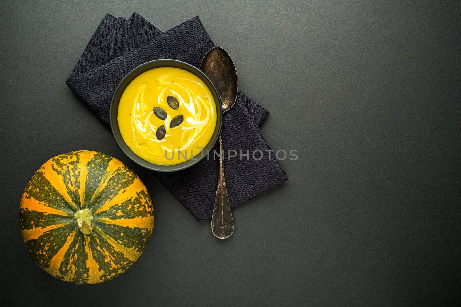 Pumpkin and vegetable soup with cream on dark background Top view