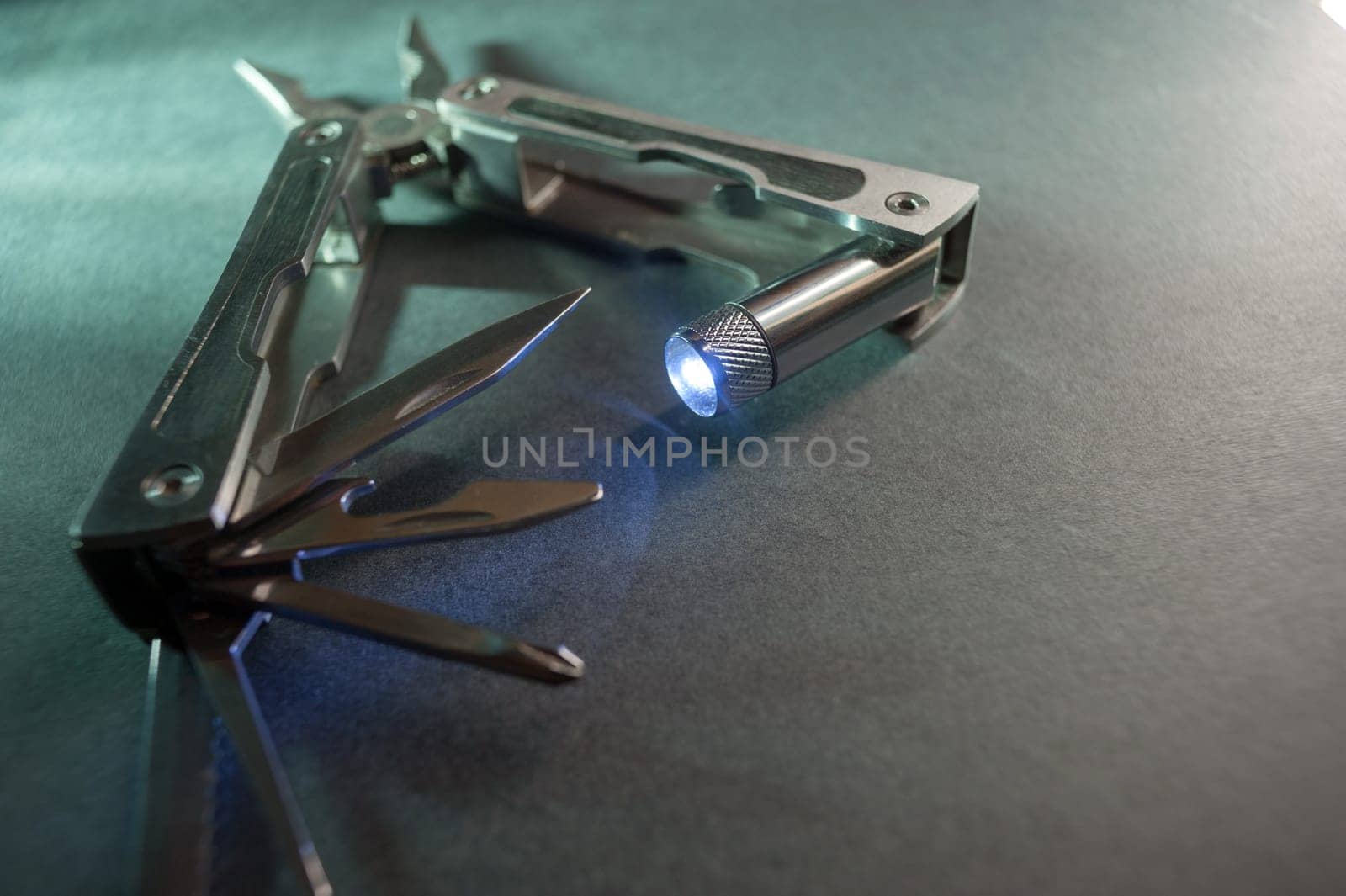 Combined pliers, multifunctional, with flashlight. Against the background of a gray texture.