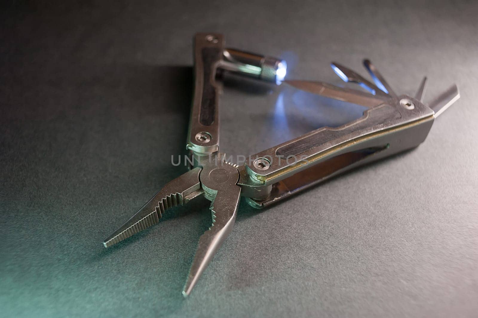 Combined pliers, multifunctional, with flashlight. Against the background of a gray texture.