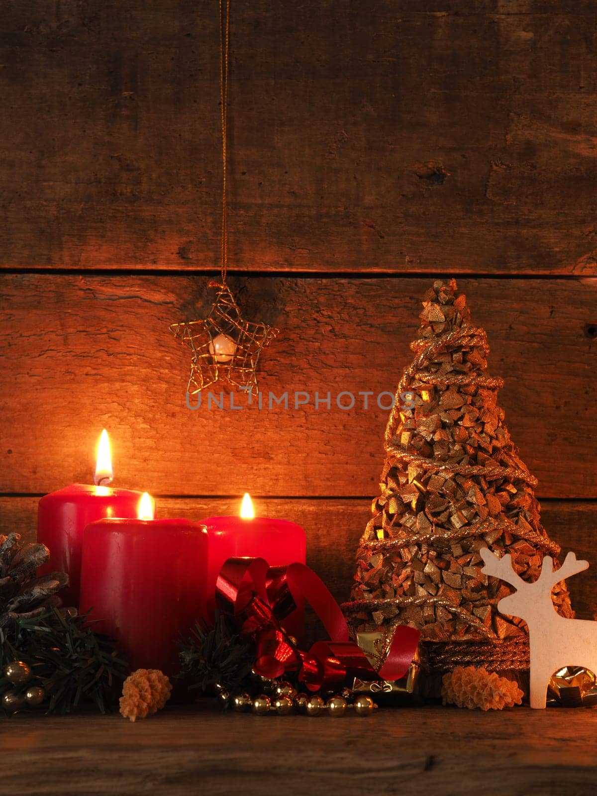 Romantic Christmas background with three burning candles on a wooden table